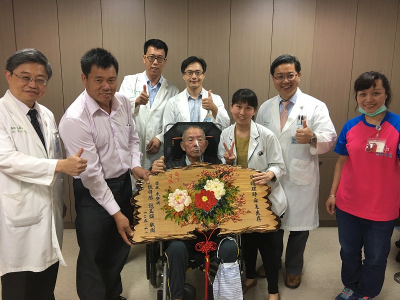 吳錫金院長（左）偕醫護同仁參與患者張得勝先生（坐輪椅者）贈匾。